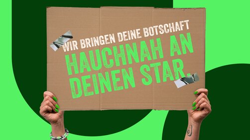 Wir bringen deine Botschaft hauchnah an deinen Star - hochgehaltenes Schild zur Konzertaktion 09.05.25 in Berlin